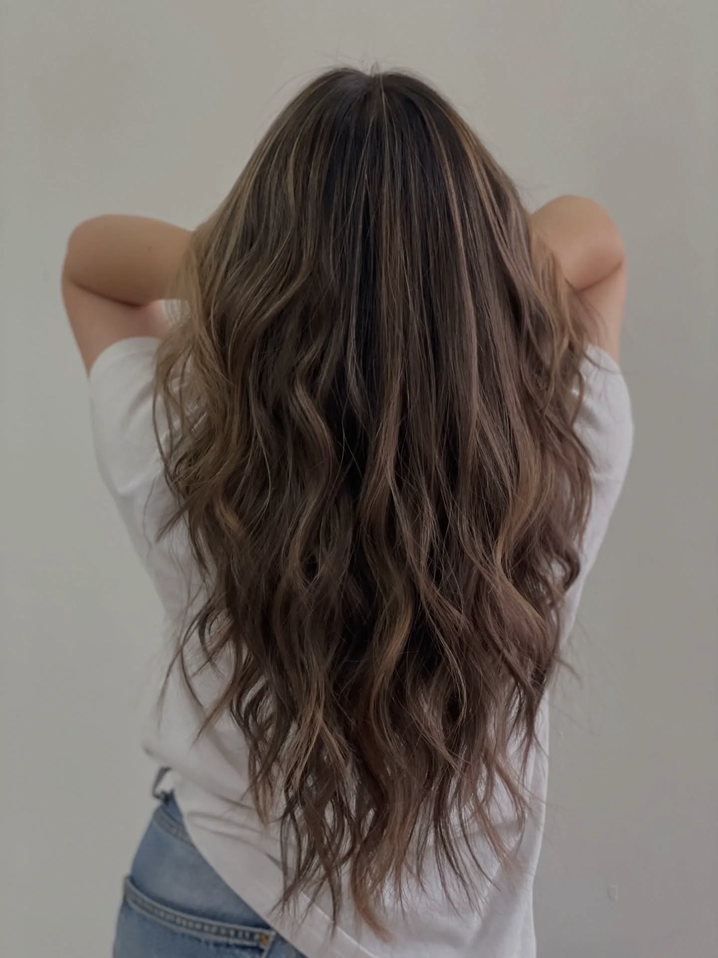 Long brown hair with balayage highlights, styled in soft waves at Sense.